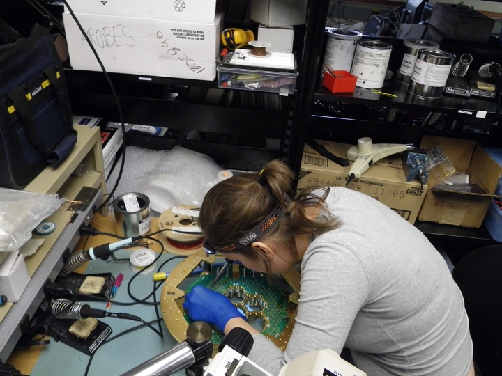 Abby Crites touching up solder joints on the PCB board connecting to the 90 GHz pixels. 